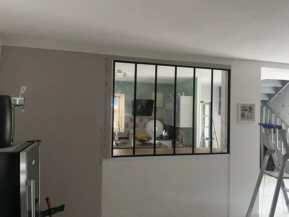 Cloison vitrée de type atelier montée en plâtrerie, séparant deux espaces intérieurs