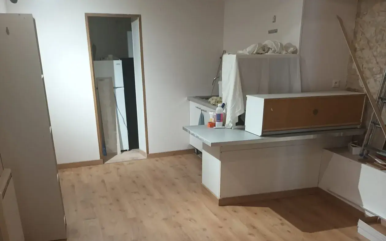 Cuisine en cours de finition : sol stratifié posé, murs repris et pan de mur en pierre laissé apparent