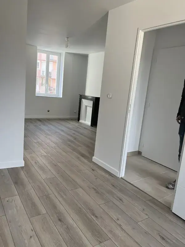 Pièce livrée, sol à décor bois gris continu vers la pièce voisine, plinthes blanches posées