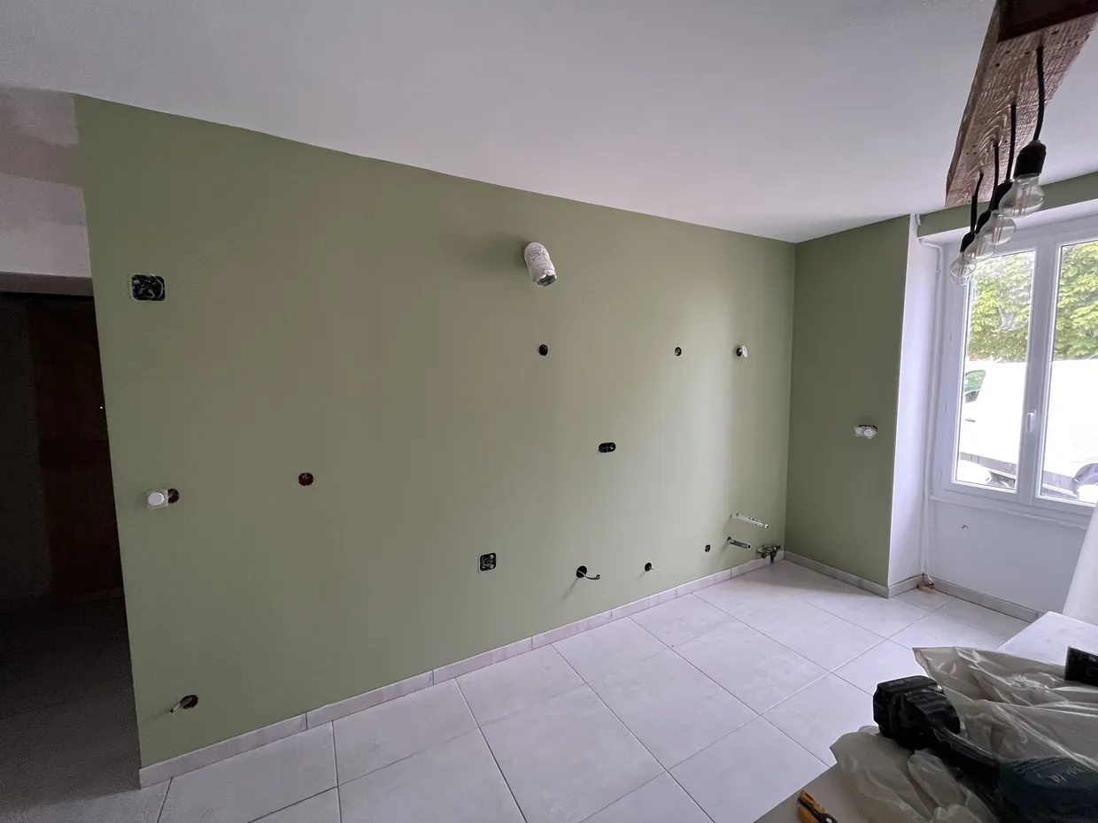 Mur de cuisine peint en vert olive sur toute sa largeur, plafond blanc, sol carrelé clair