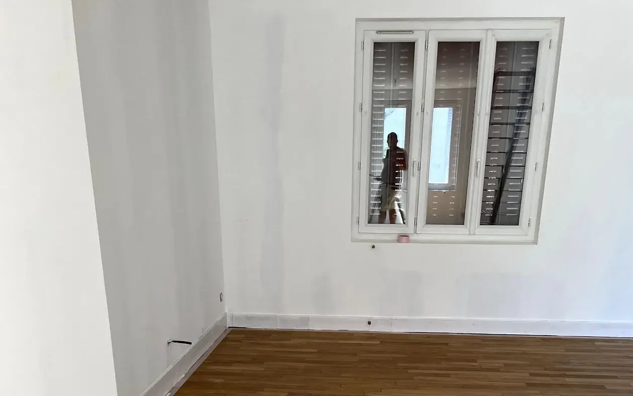 Pièce en cours de chantier : murs et plafond repris en blanc, parquet chêne conservé et protégé sous bâche
