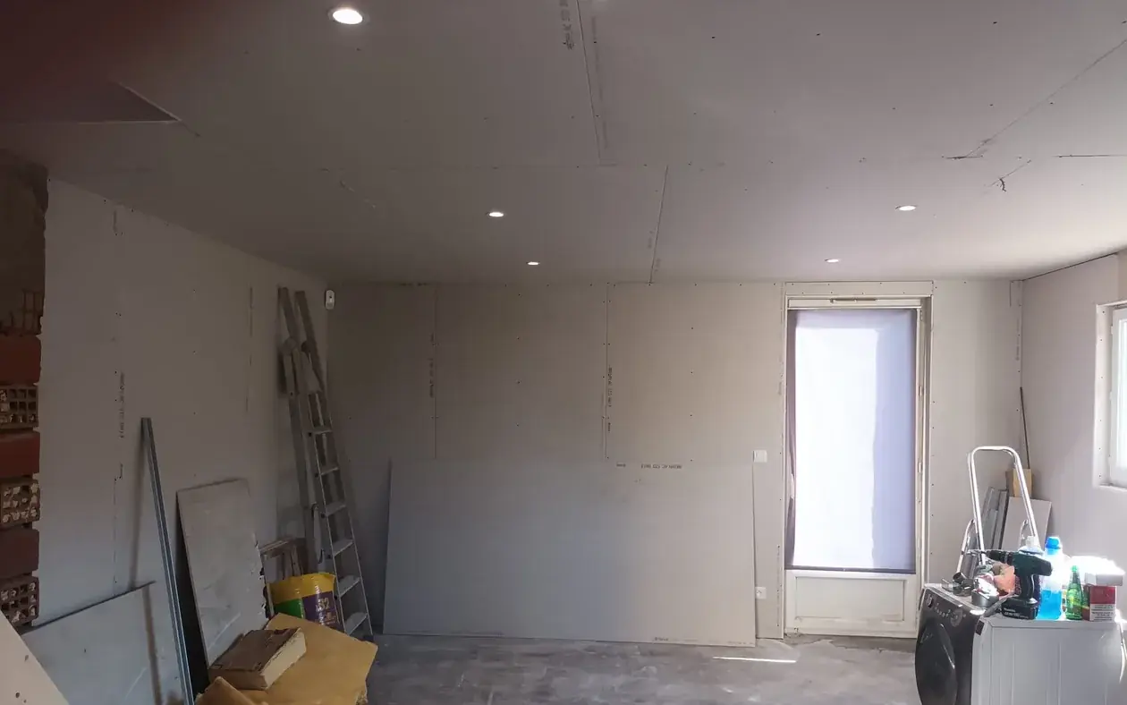 Plafond en plaques de pl&acirc;tre avec spots encastr&eacute;s, doublage des murs et mur en brique laiss&eacute; apparent