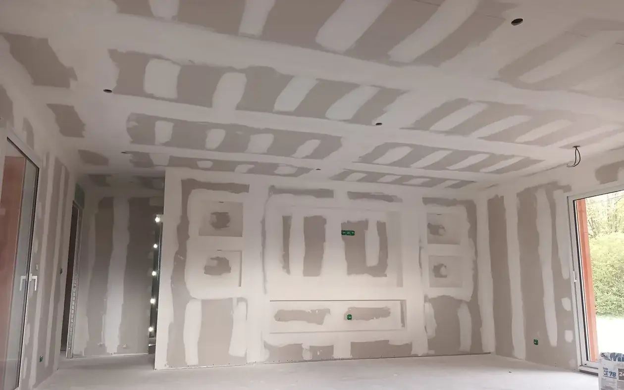 Plafond dont les poutres sont habill&eacute;es en plaques de pl&acirc;tre et mur &agrave; niches, bandes &agrave; joint termin&eacute;es