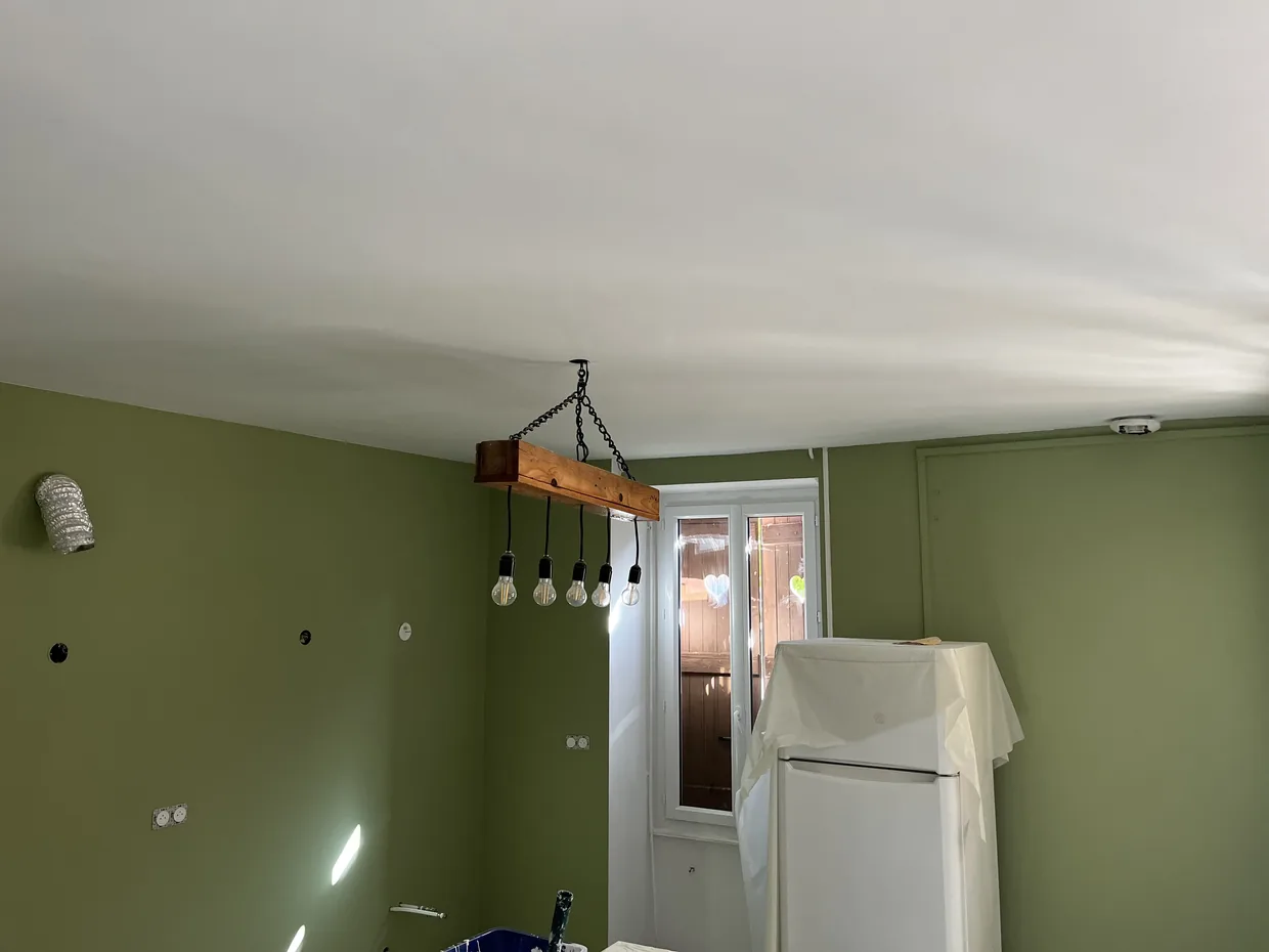 Raccord entre un mur vert et un plafond blanc, ligne de coupe nette réalisée au pinceau