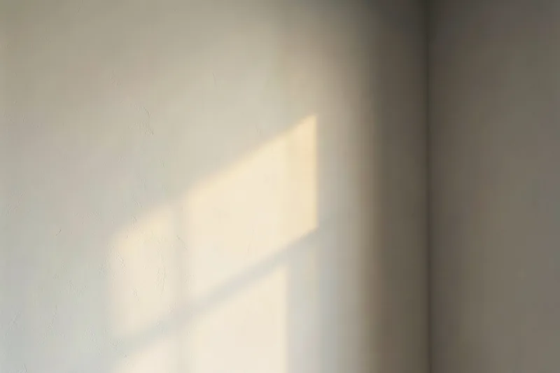 Mur intérieur lissé et prêt à peindre, révélé par la lumière rasante d'une fenêtre